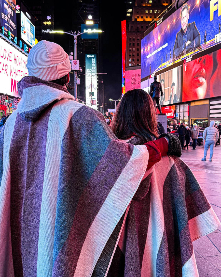 Pareja de espaldas con ponchos a rayas en Times Square, de noche