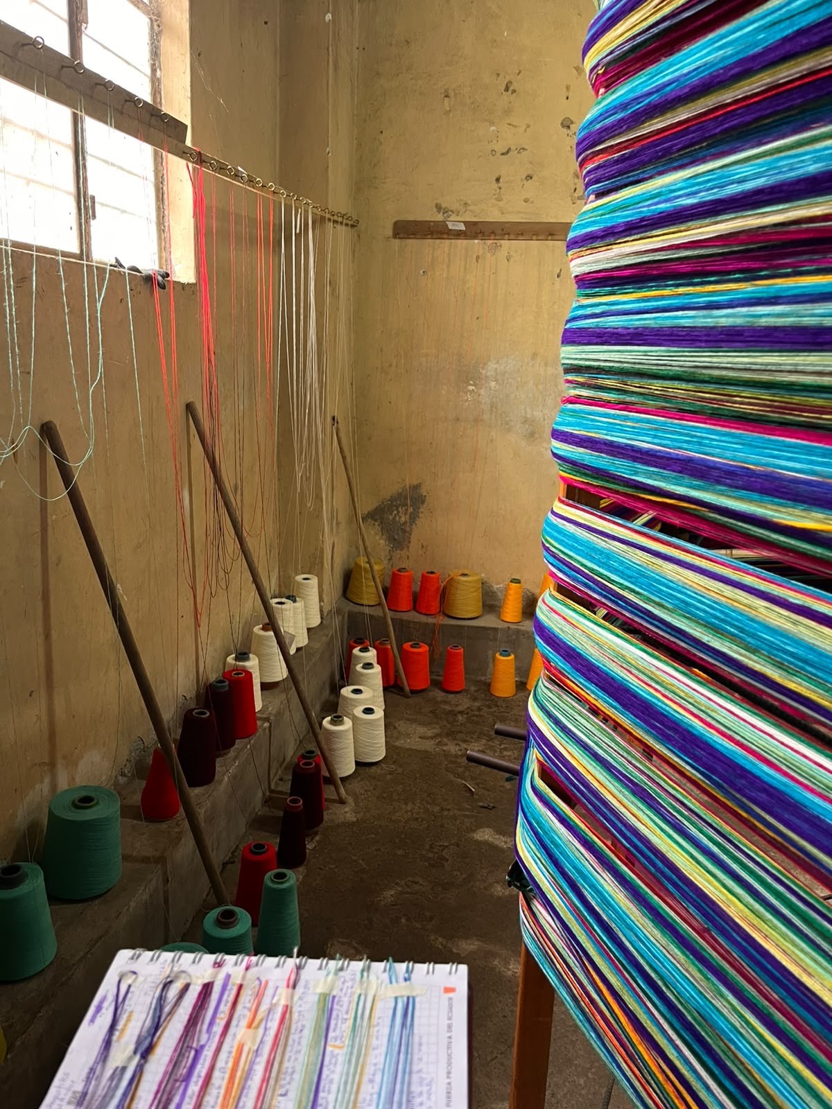 Rincón de un taller de Peguche con conos de hilo de colores y la urdimbre multicolor