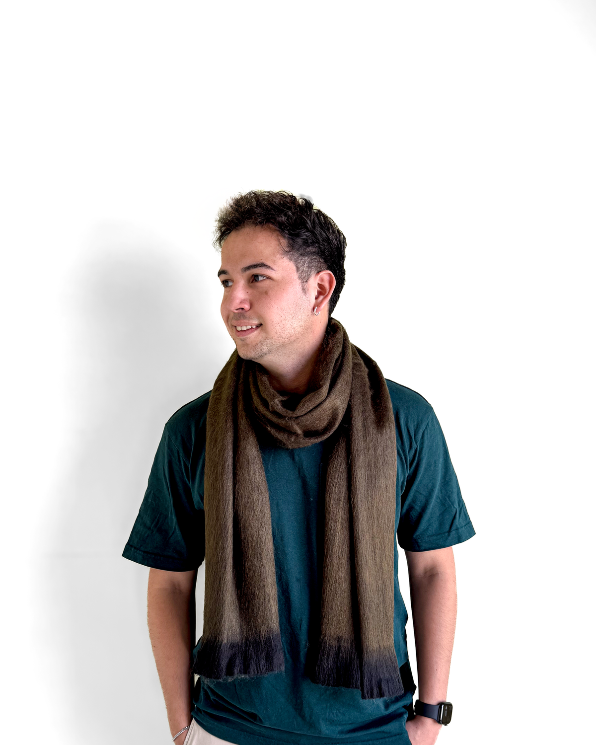 Chal de alpaca Oliva Profundo usado como bufanda por un modelo con camiseta verde que mira hacia un lado