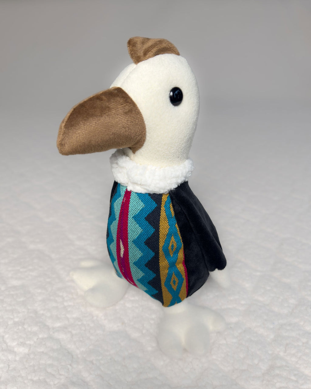 Peluche Kuri, cóndor bordado a mano con pico café, cuello blanco y cuerpo de tela andina, de tres cuartos