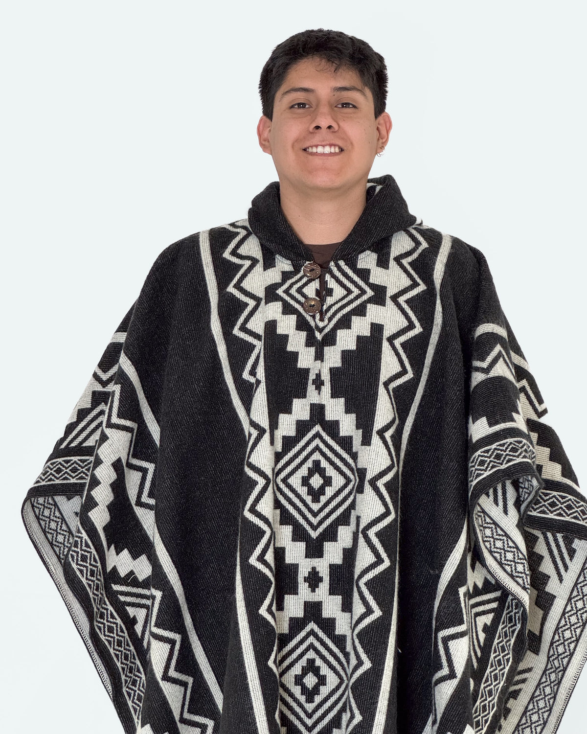 Hombre sonriendo de medio cuerpo con el poncho Chimborazo negro y crema, con botones de coco