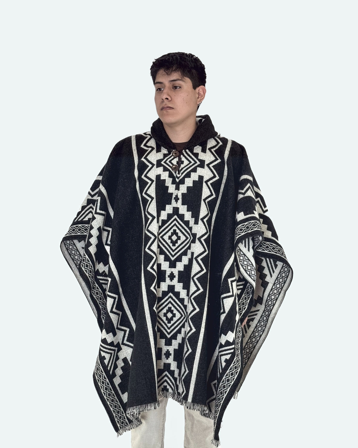 Hombre de tres cuartos mirando de lado con el poncho Chimborazo negro con rombos crema