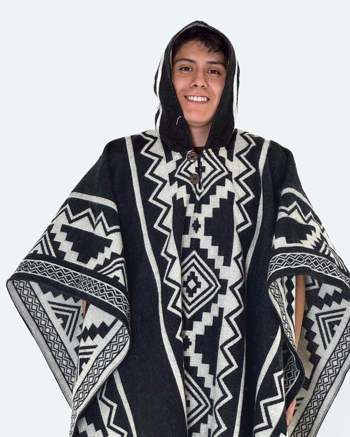 Hombre sonriendo con la capucha puesta y el poncho Chimborazo negro y crema de rombos