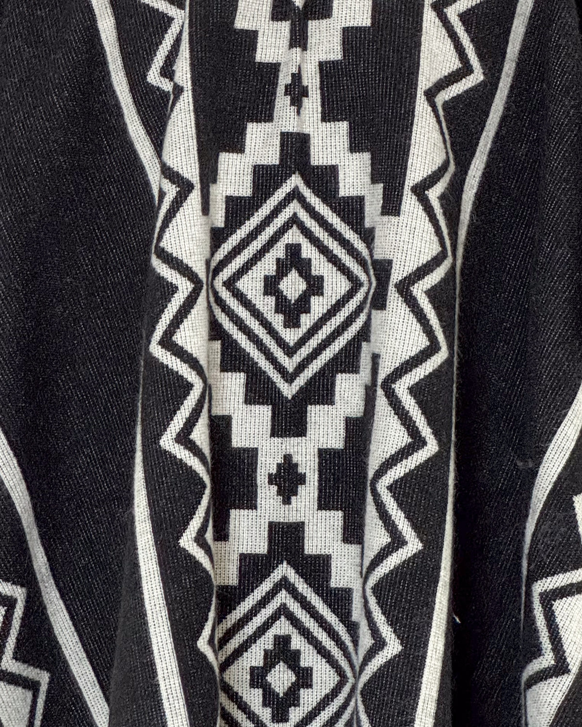 Detalle del rombo escalonado crema sobre el tejido negro del poncho Chimborazo