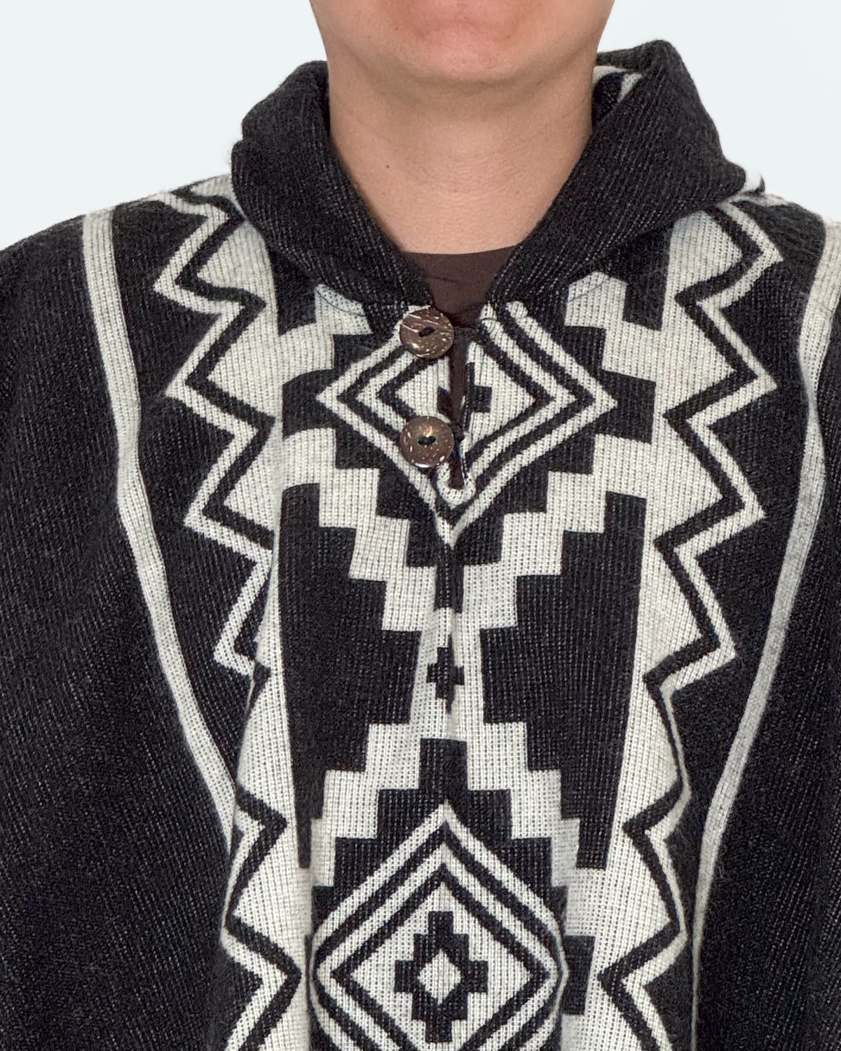 Detalle del cuello con dos botones de coco y el rombo central crema del poncho Chimborazo
