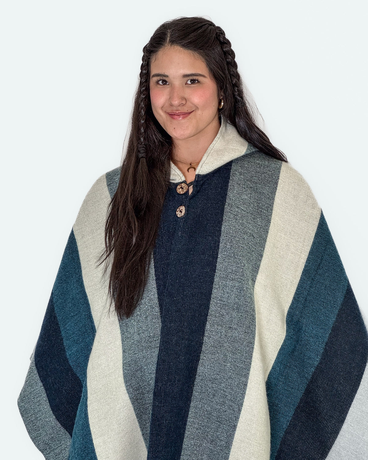 Mujer sonriendo de medio cuerpo con el poncho Cuicocha de franjas azules, grises y crema, con dos botones de coco