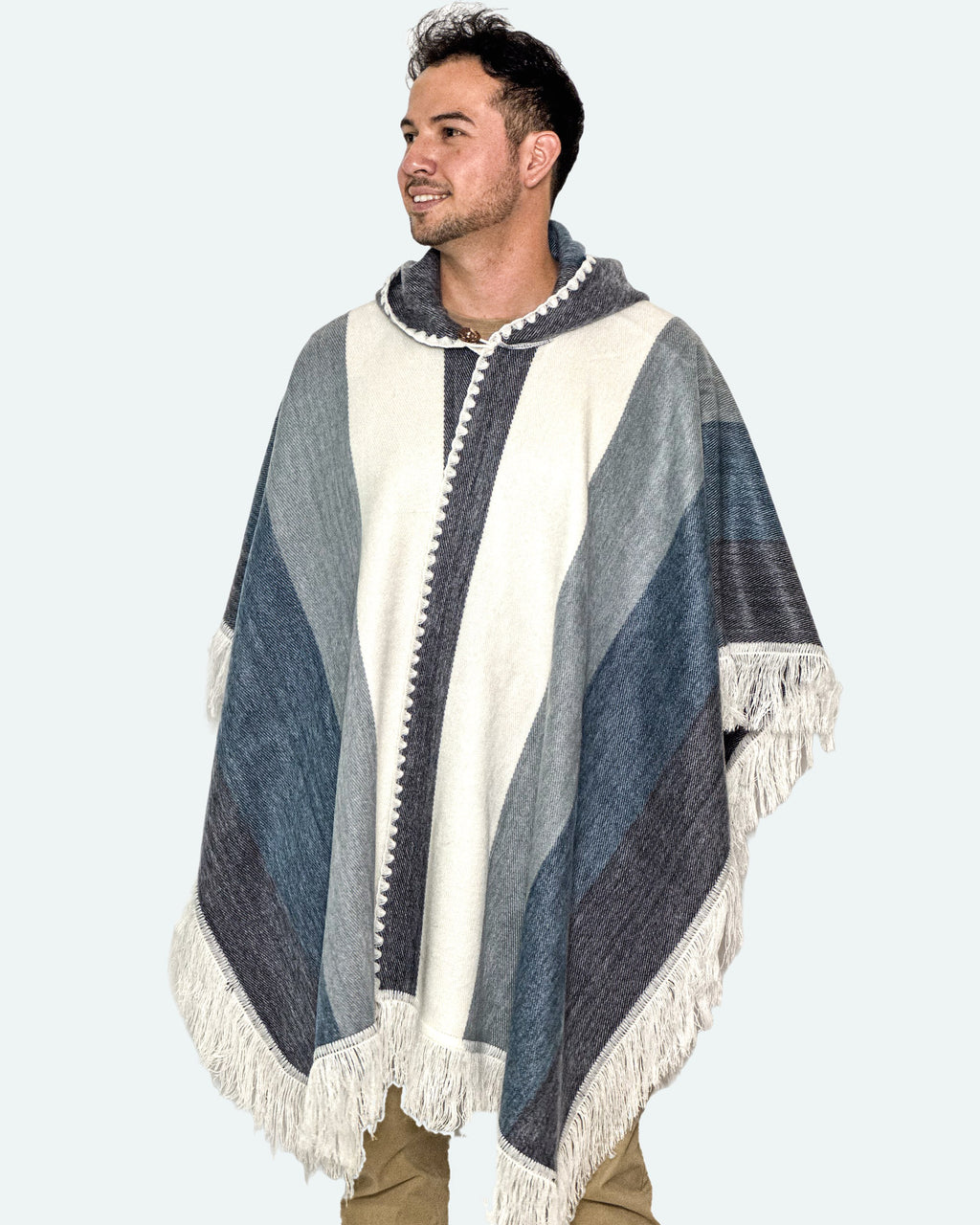Hombre de medio cuerpo mirando de lado con el poncho Espíritu Cielo Andino de franjas azules y blancas