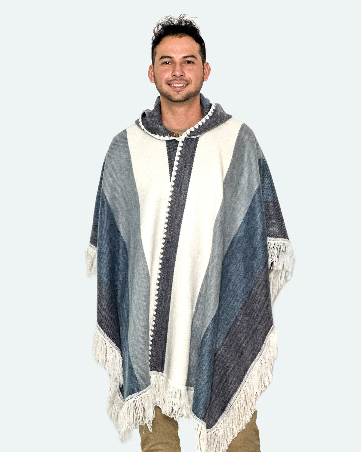 Hombre sonriendo de tres cuartos con el poncho Espíritu Cielo Andino abierto adelante, con flecos blancos