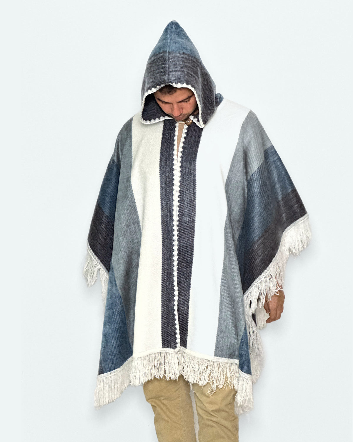 Hombre con la capucha puesta y la mirada hacia abajo con el poncho Espíritu Cielo Andino