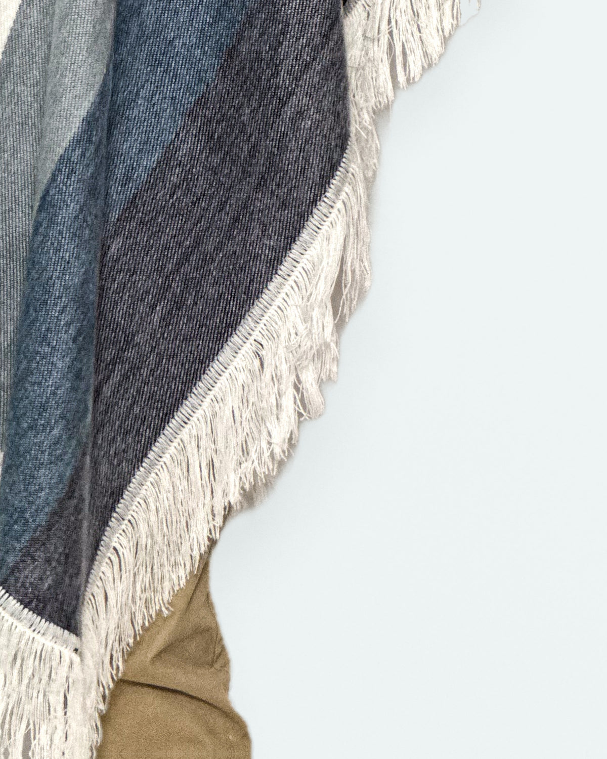 Detalle de los flecos blancos y la franja azul oscuro del borde del poncho Espíritu Cielo Andino