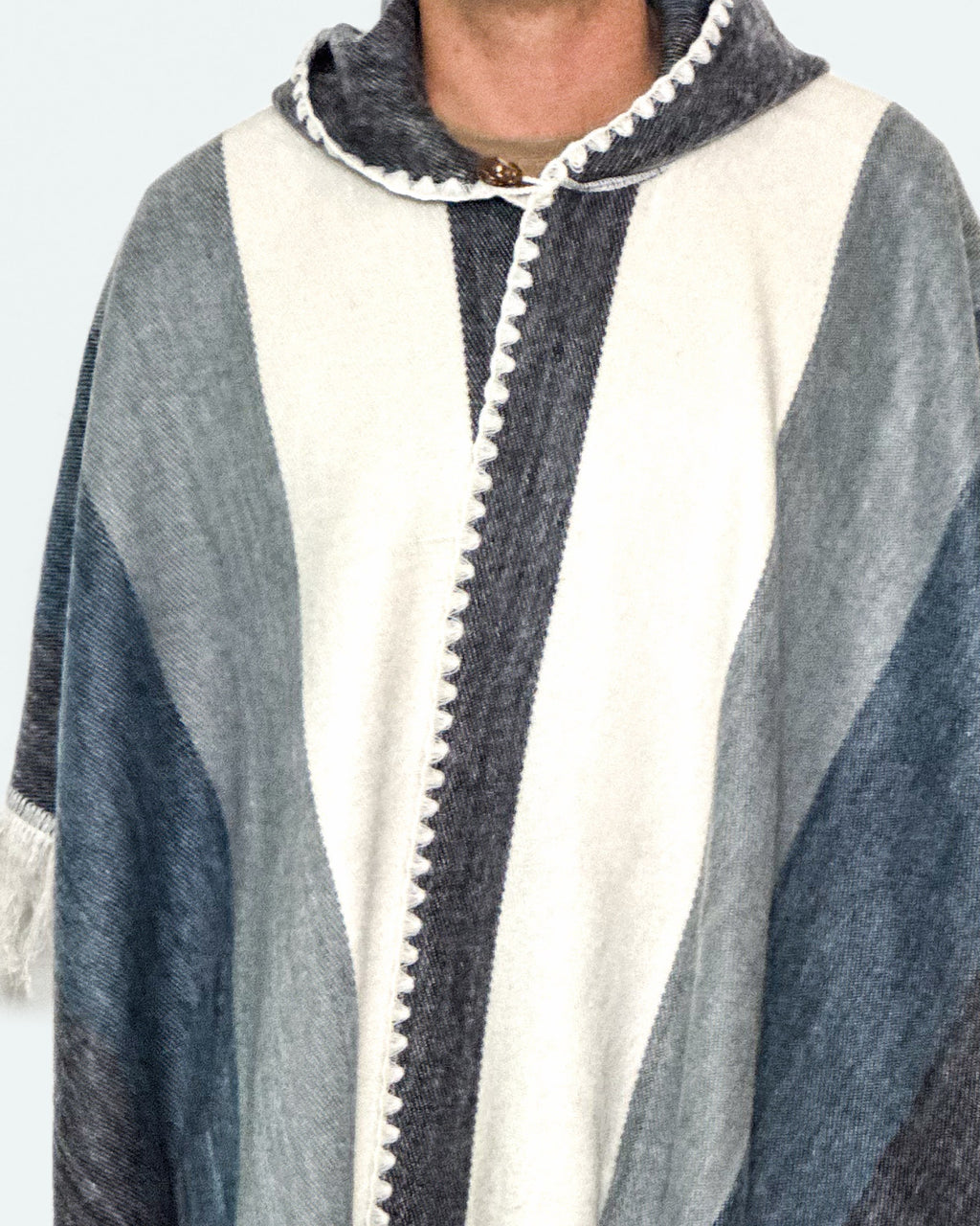 Detalle del cuello y la capucha con borde blanco del poncho Espíritu Cielo Andino de franjas azules y grises