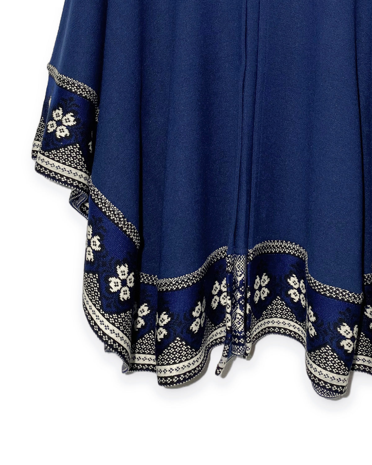 Detalle del borde inferior con flores blancas y franjas crema del Poncho Flor de Imbabura