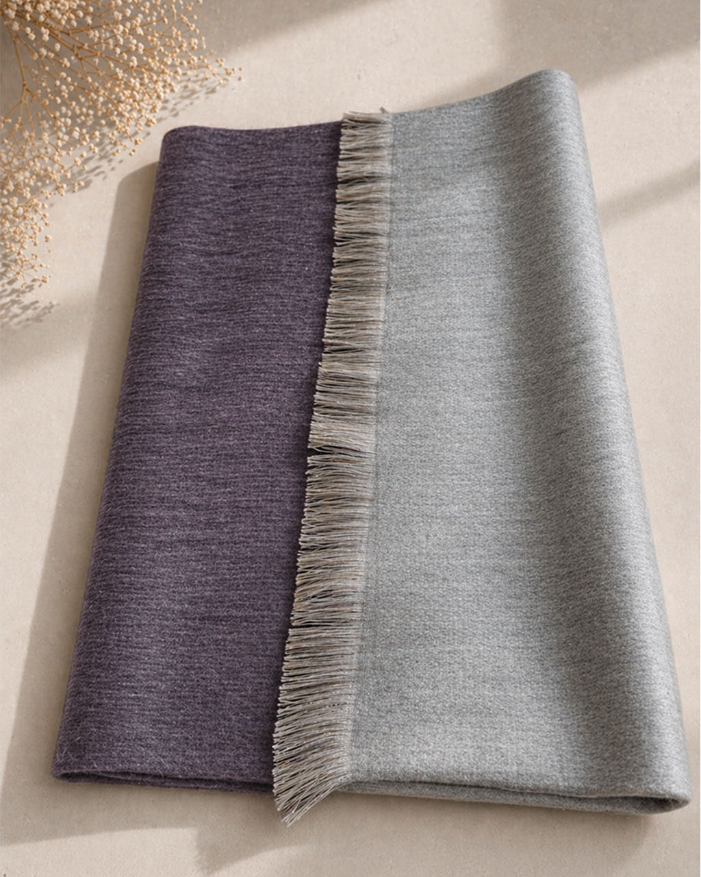 Chal de alpaca doble cara Acero doblado sobre una mesa, gris oscuro de un lado y gris claro del otro