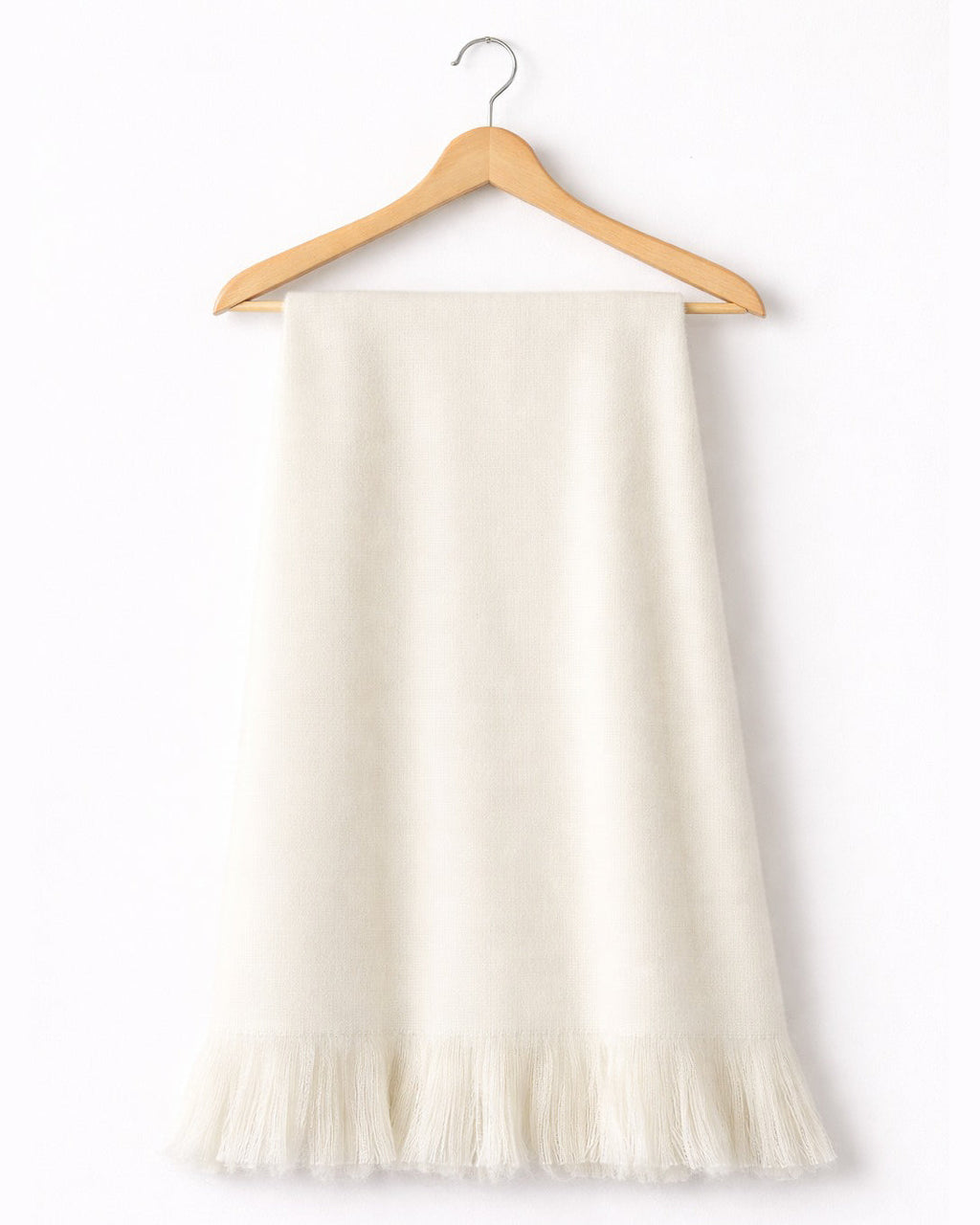 Chal de alpaca Marfil Natural con flecos, colgado de una percha de madera sobre fondo blanco