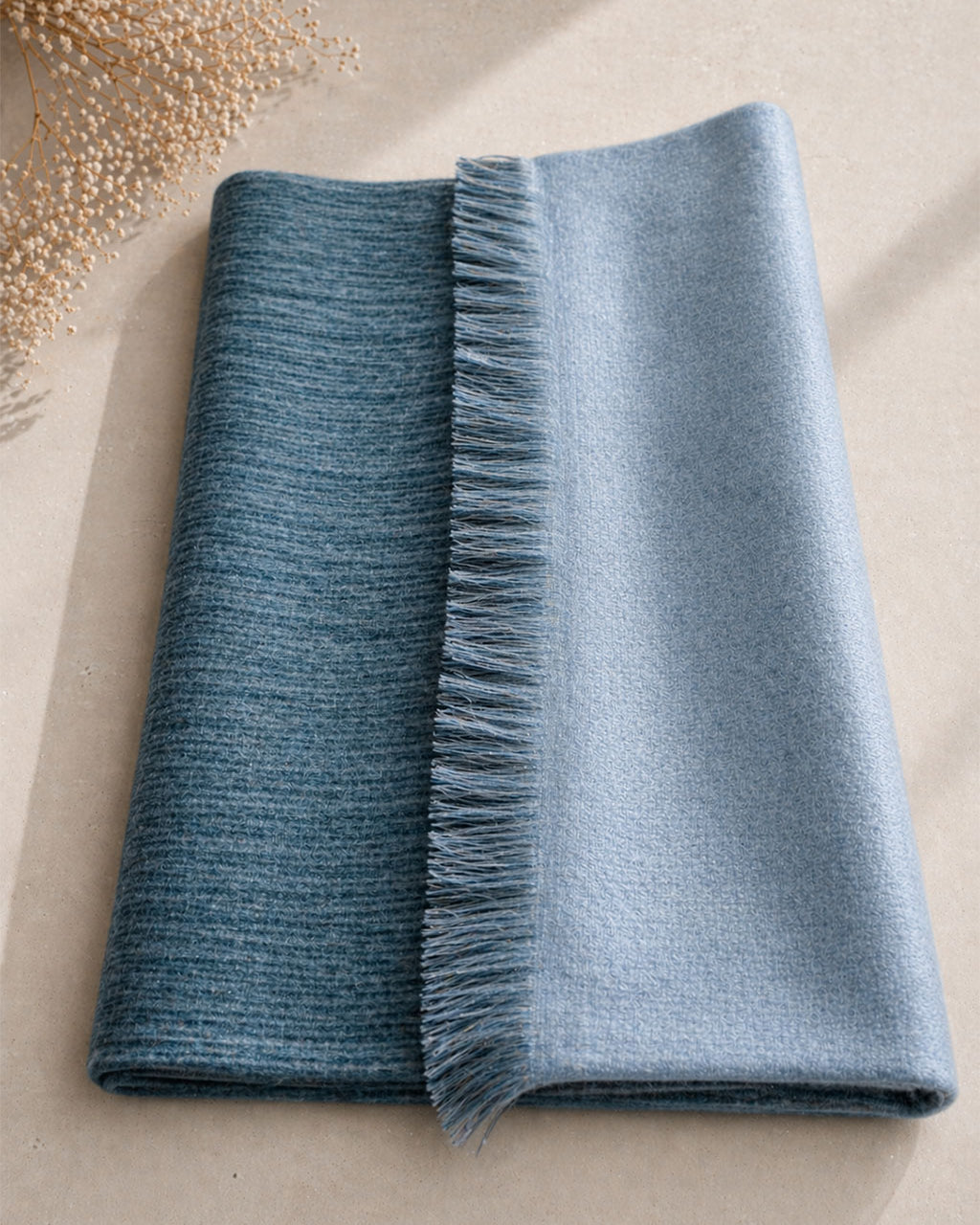 Chal de alpaca doble cara Niebla doblado sobre una mesa, gris azulado profundo de un lado y claro del otro