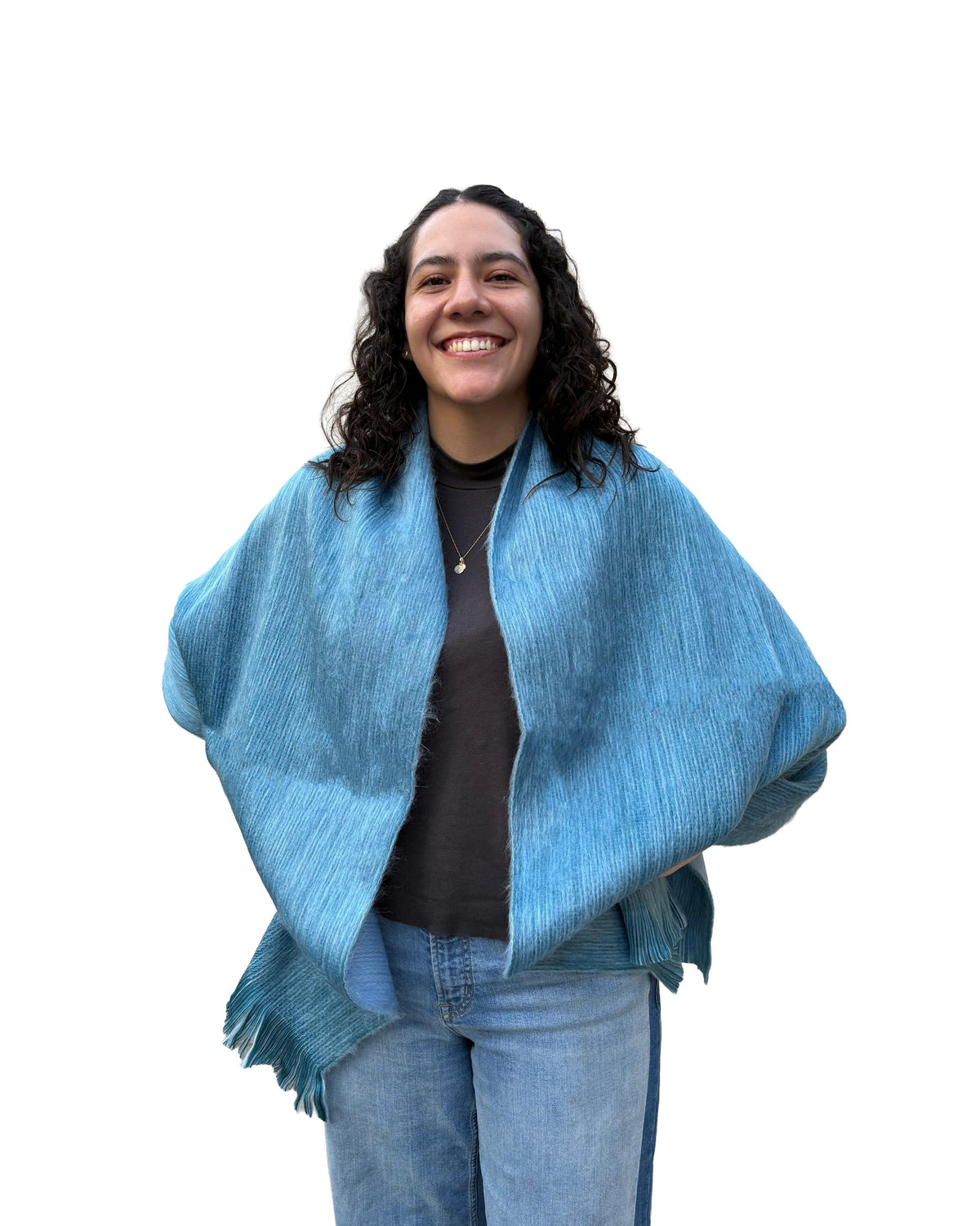 Chal de alpaca doble cara Niebla en gris azulado, sobre los hombros de una modelo sonriente con jeans