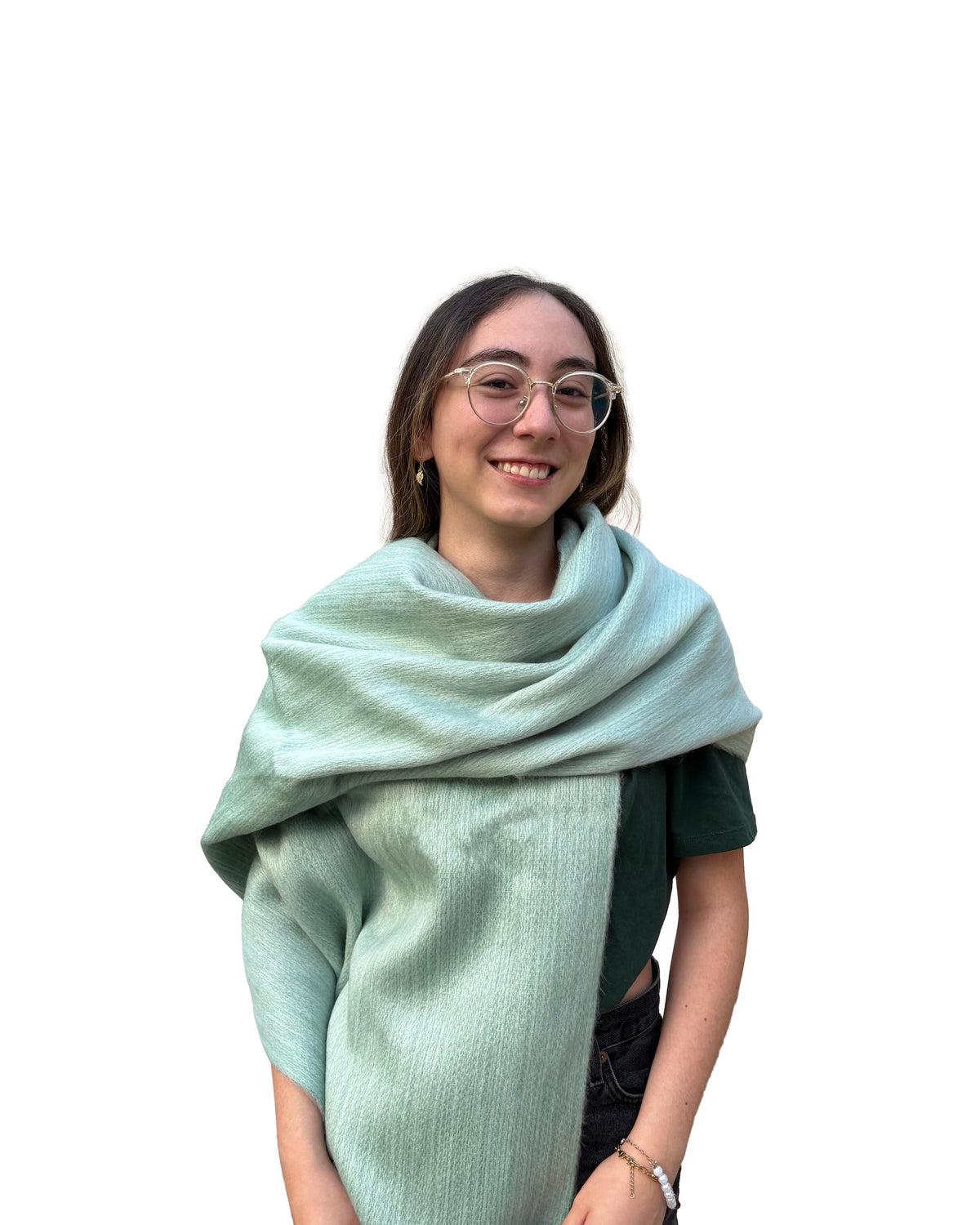Chal de alpaca doble cara Salvia en verde salvia, envuelto al cuello y los hombros de una modelo con lentes