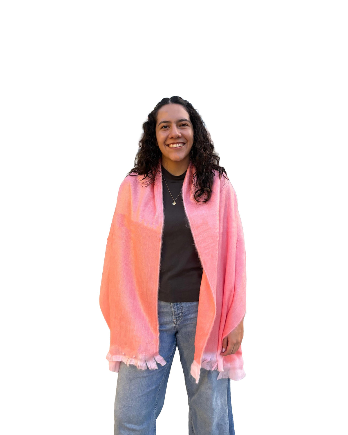 Chal de alpaca Coral Blush en coral y rosa suave, sobre los hombros de una modelo sonriente con jeans