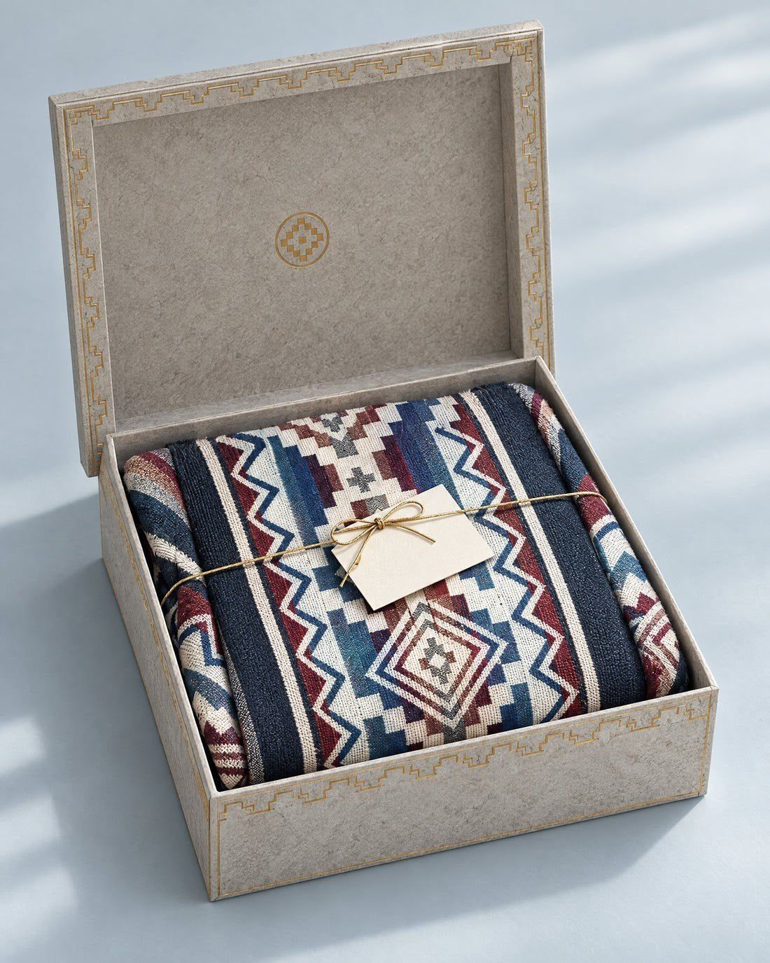 Caja de regalo abierta con un poncho doblado y una tarjeta