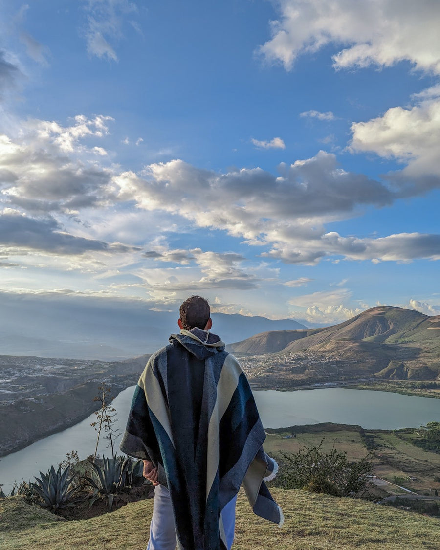 De espaldas con poncho a rayas en La Estelita, con la laguna de Yahuarcocha al fondo
